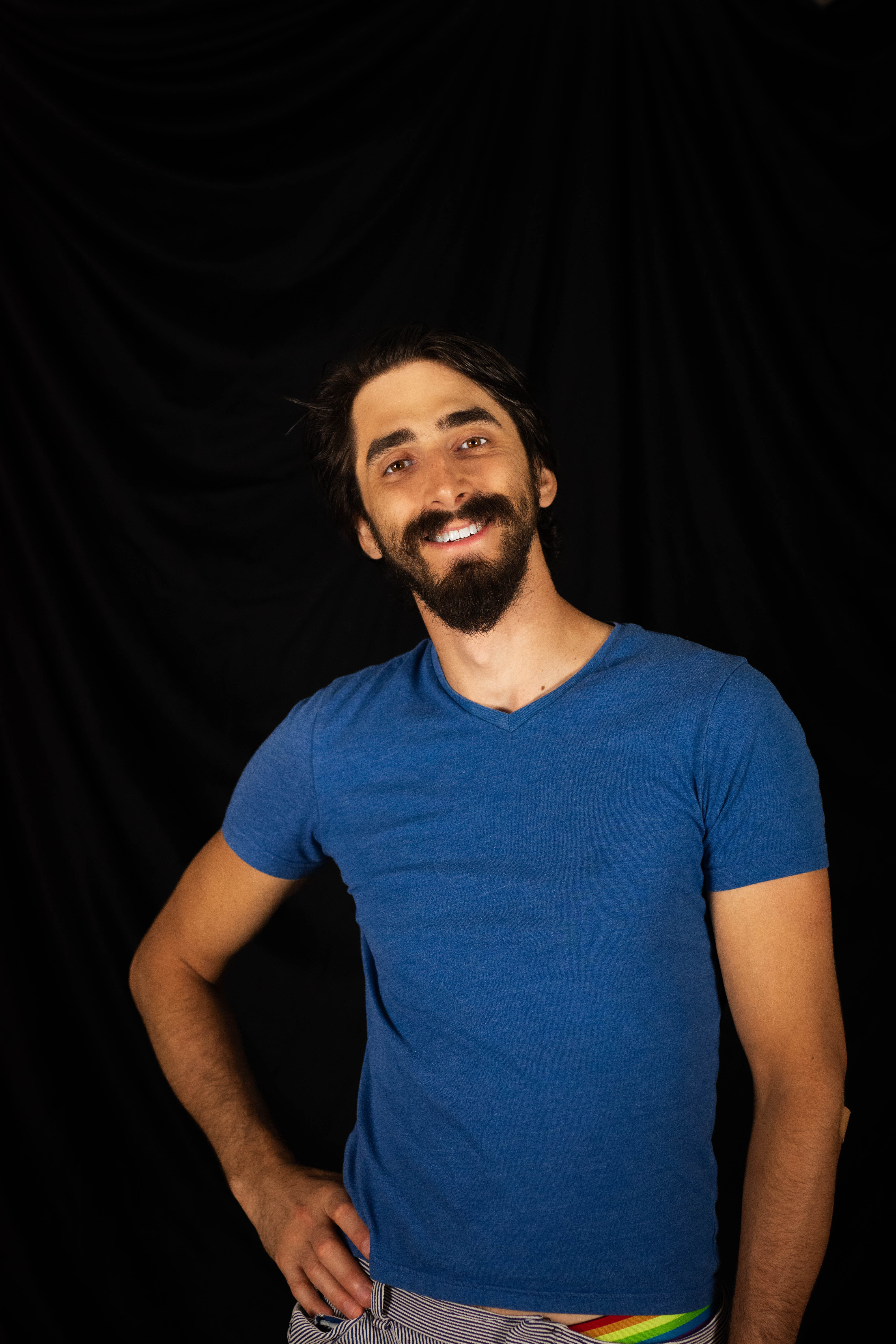 Nick, a man with a mustache and goatee, smiles at the camera wearing a blue t shirt